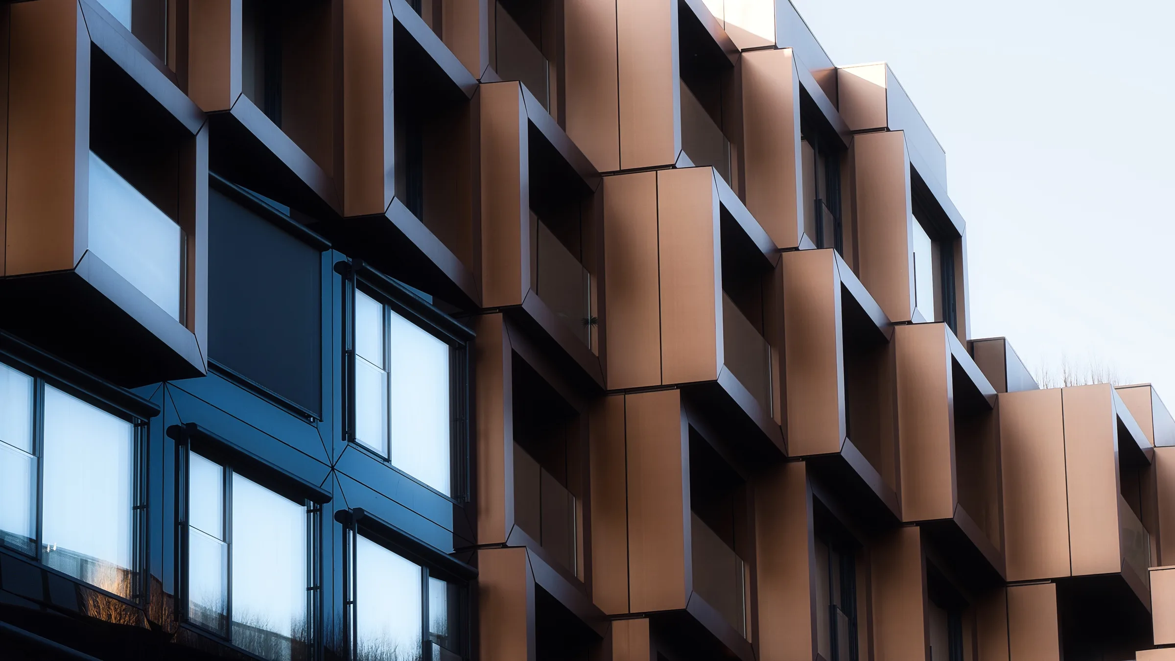 Folded metal panels on a building facade, the same geometry as the mark