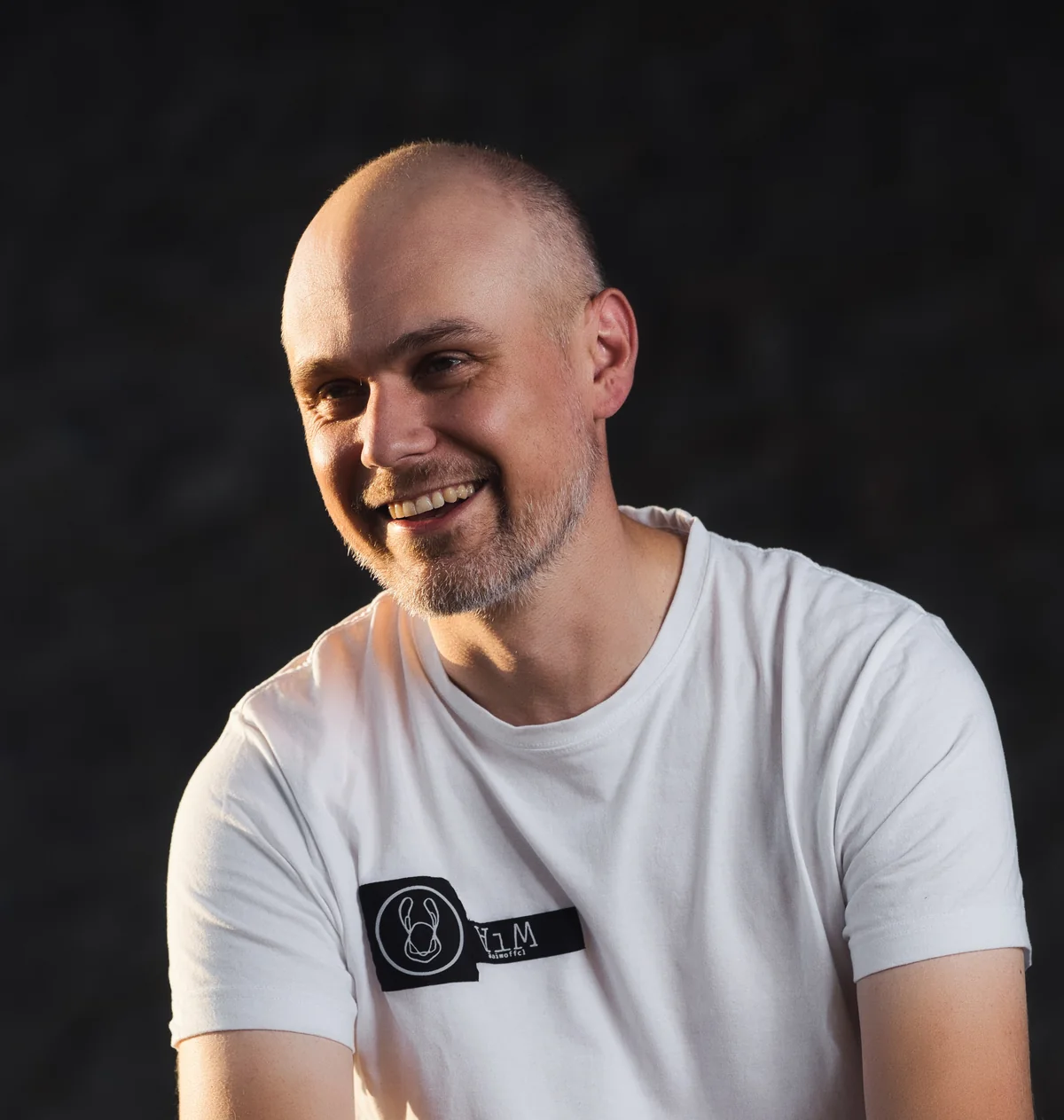 Martin Hronec, laughing, against the dark concrete